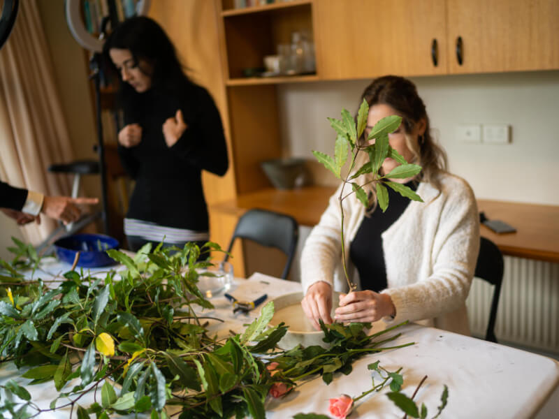 A lot of green foliage on a table at a flower arranging workshop.